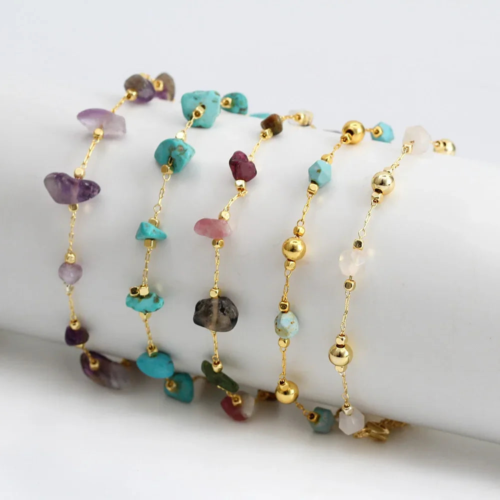 Gold chain bracelets with natural gemstone beads in various colors, displayed on a white roll.