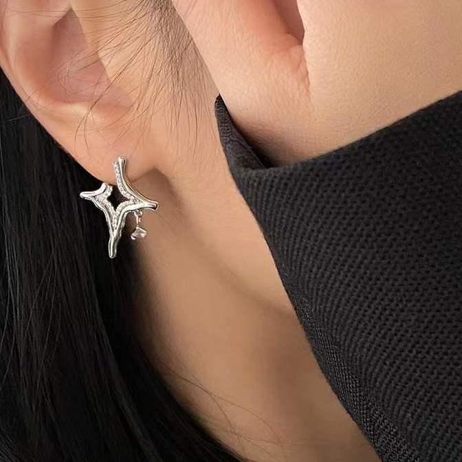 Close-up of a woman's ear wearing a unique silver star-shaped stud earring