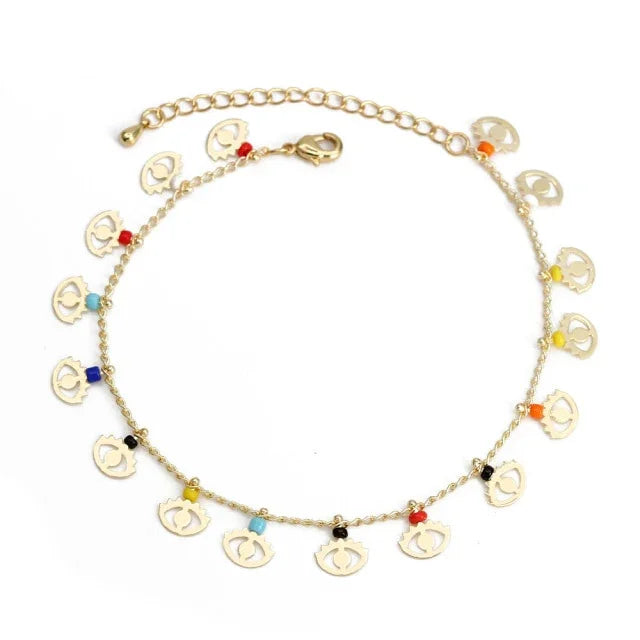 Gold bracelet with multicolored beads and small anchor charms on white background