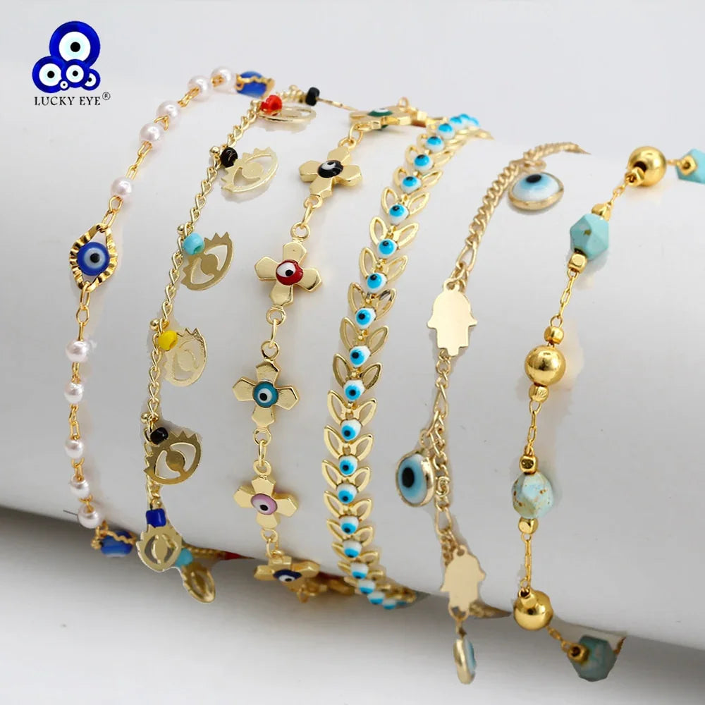 Gold evil eye bracelets with colorful beads and charms, displayed on a white holder.