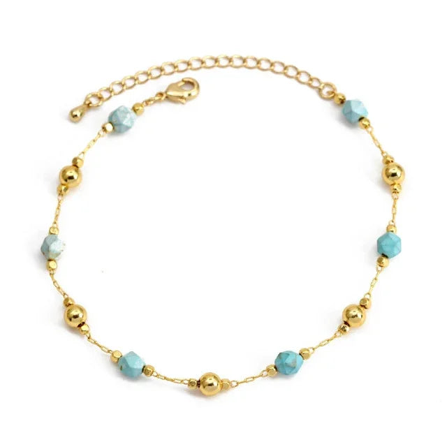 Gold chain bracelet with turquoise beads and gold round accents on white background