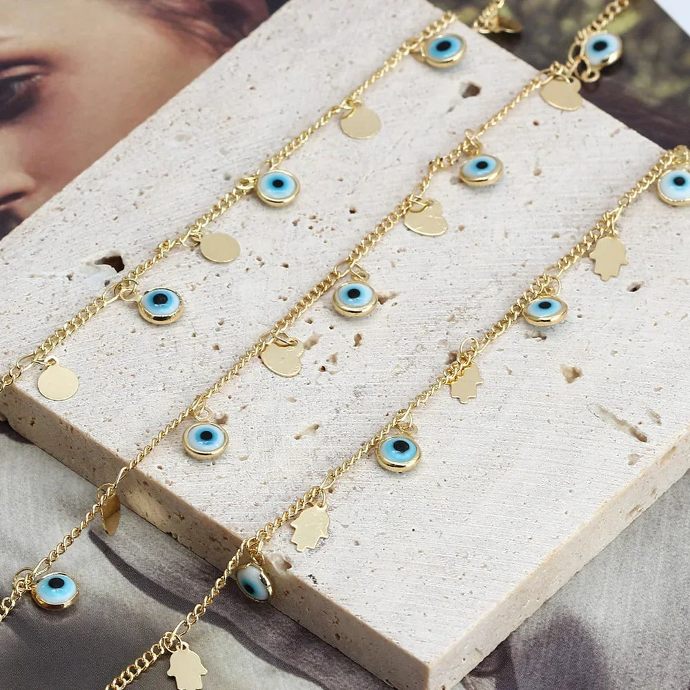 Gold bracelet with blue evil eye charms and hamsa pendants on stone surface