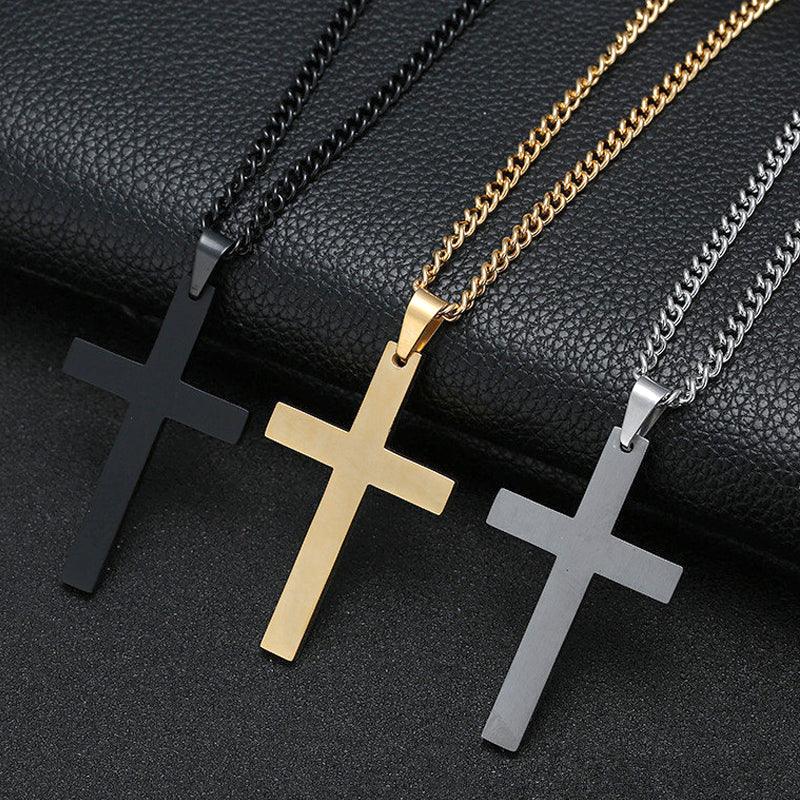 Three metal cross pendant necklaces in black, gold, and silver on a textured black surface.