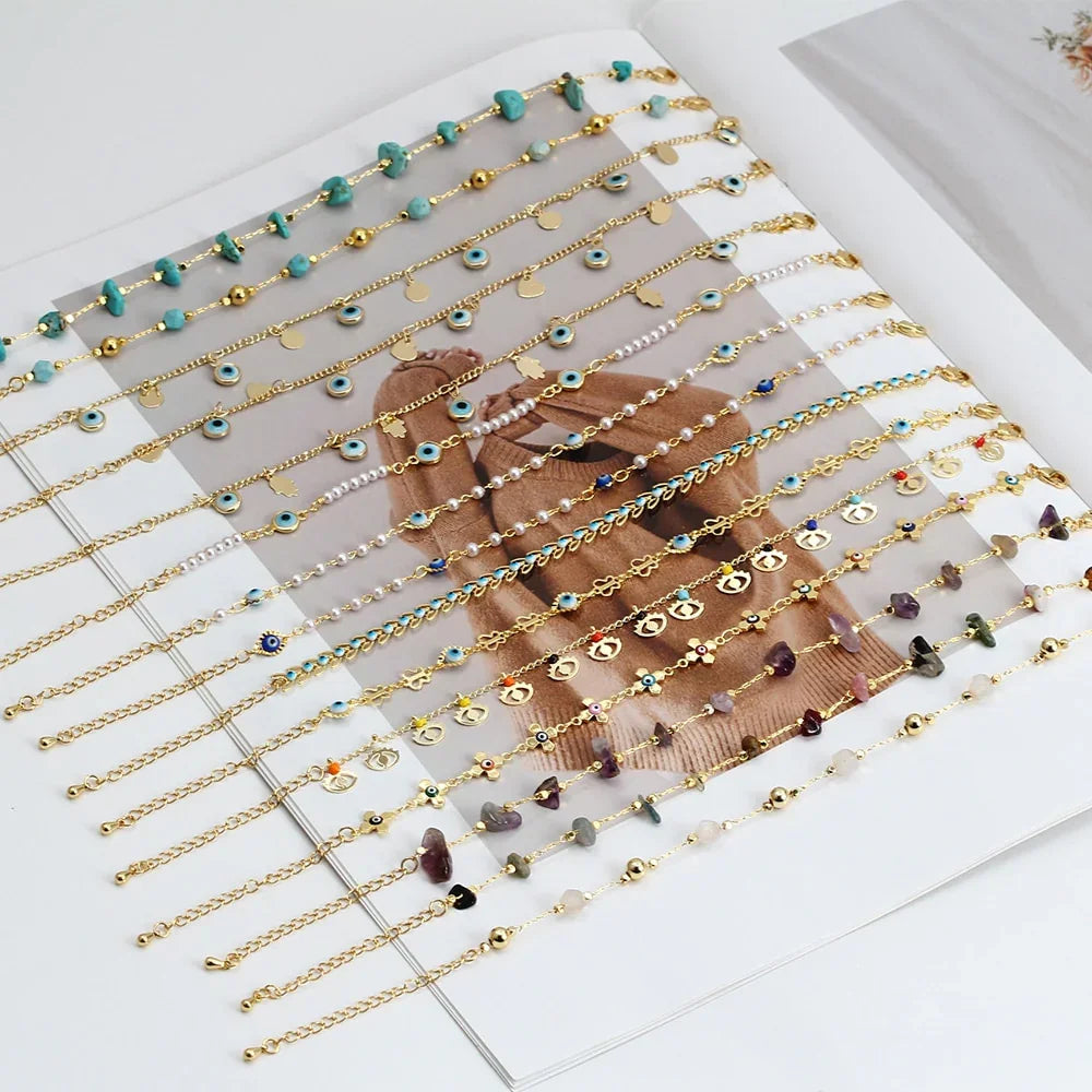 Assorted gold chain bracelets with colorful charms and beads displayed on a magazine