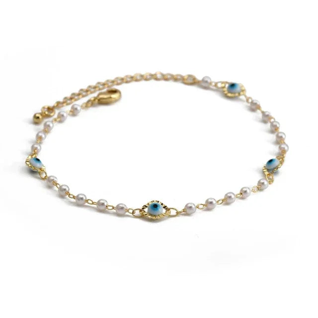 Gold bracelet with small pearls and blue evil eye charms on white background